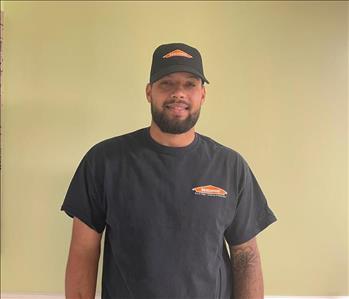 Man standing against a green wall with a SERVPRO shirt on